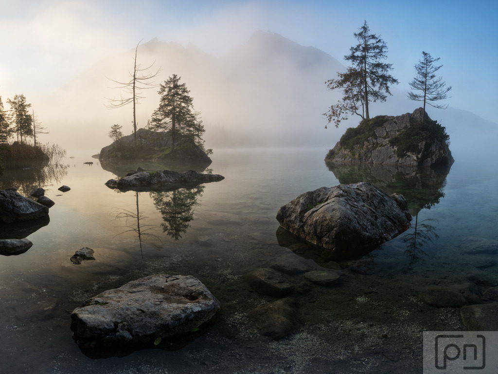 Der Hintersee in Berchtesgaden bei Sonnenaufgang | Ein Sonnenaufgang am Hintersee in Berchtesgaden ist ein wahres Naturschauspiel, das die Seele berührt. Wenn die ersten Strahlen der Sonne die umliegenden Berge und den klaren See streifen, erwacht die Welt in einer magischen Stille. Das warme Licht taucht die Szenerie in sanfte Gold- und Rosatöne und spiegelt sich in der glatten Wasseroberfläche des Hintersees wider.
