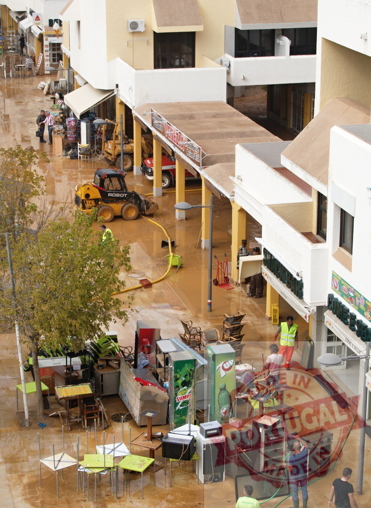 Workers cleaning muddy street after devastating flood | Albufeira Flood - discruction by weather problems People and machinery cleaning a mud-filled urban street after a natural disaster - Realized with Pictrs.com