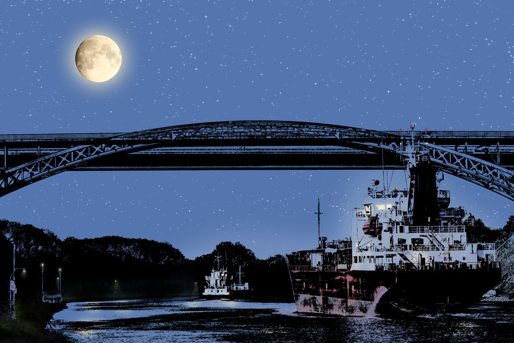 Photoart Moonlight: Nord-Ostsee-Kanal bei Nacht | Dieses Wandbild im Querformat zeigt die künstlerische Interpretation der Levensauer Hochbrücke bei Nacht. Auf dem Nord-Ostsee-Kanal sind zwei Frachter im Mondschein zu sehen. Am Himmel leuchtet der Mond und zahlreiche Sterne. Somit erhalten Sie ein exklusives Kunstwerk der Ostseeregion. Zudem ist dieses Bild ein Teil der Photoartserie Moonlight in der weitere maritime Orte im Mondlicht gezeigt werden.   - Realisiert mit Pictrs.com