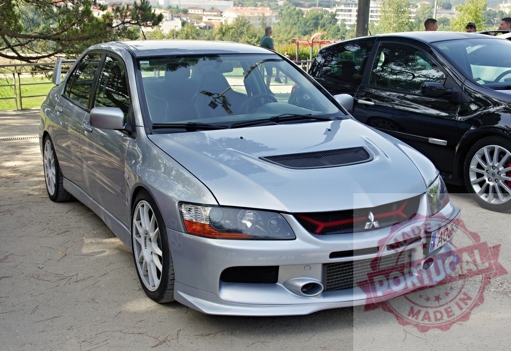 Silver Mitsubishi Lancer Evolution parked near a park | Tuned silver Mitsubishi Lancer Evolution VIII parked near a park, reflecting the surrounding trees - Realized with Pictrs.com