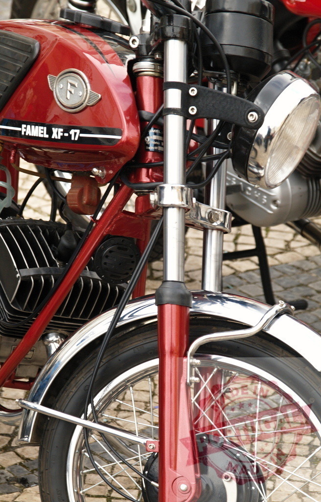 Red Famel XF-17 motorcycle parked on cobblestone street | Close-up of a shiny red vintage Famel XF-17 motorcycle, parked on a cobblestone street, showcasing its classic design - Realized with Pictrs.com