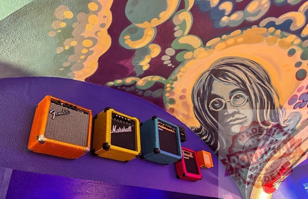 John Lennon mural with miniature Fender Marshall guitar amps | Psychedelic mural depicting John Lennon with colorful miniature guitar amplifiers and a red electric guitar - Realized with Pictrs.com