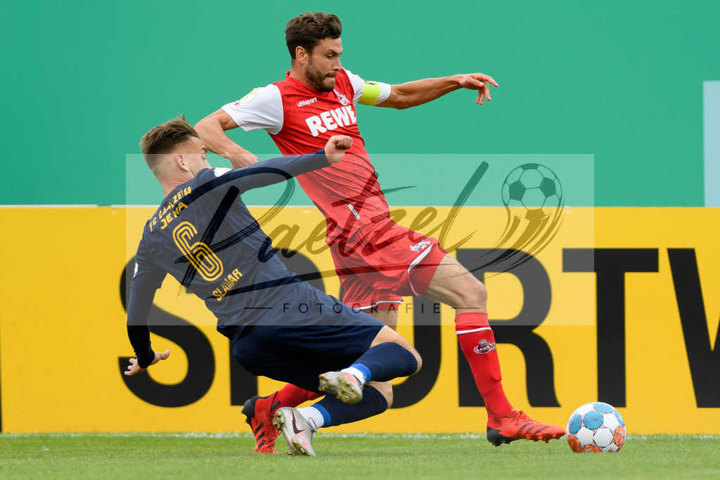 JENKOE20210808_196 | Fussball, Herren: Dennis Slamar (FC Carl Zeiss Jena) und Jonas Hector (1. FC Koeln) im Zweikampf beim Spiel der 1. Runde im DFB-Pokal zwischen FC Carl Zeiss Jena und 1. FC Koeln im Ernst-Abbe-Sportfeld am 08.08.2021 in Jena, Deutschland.DFB / DFL REGULATIONS PROHIBIT ANY USE OF PHOTOGRAPHS AS IMAGE SEQUENCES AND/OR QUASI-VIDEO. - Realisiert mit Pictrs.com