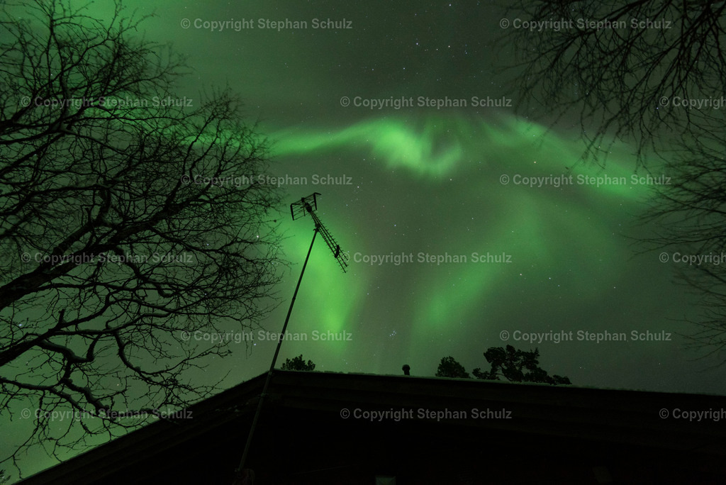 Polarlichter (Aurora Borealis) | Ein Polarlicht, das an einen Greifvogel erinnert, steht über einer Holzhütte im Pallas-Yllästunturi-Nationalpark. Polarlichter oder auch Nordlichter erinnern häufig an Fabelwesen oder riesige Vögel. - Realisiert mit Pictrs.com