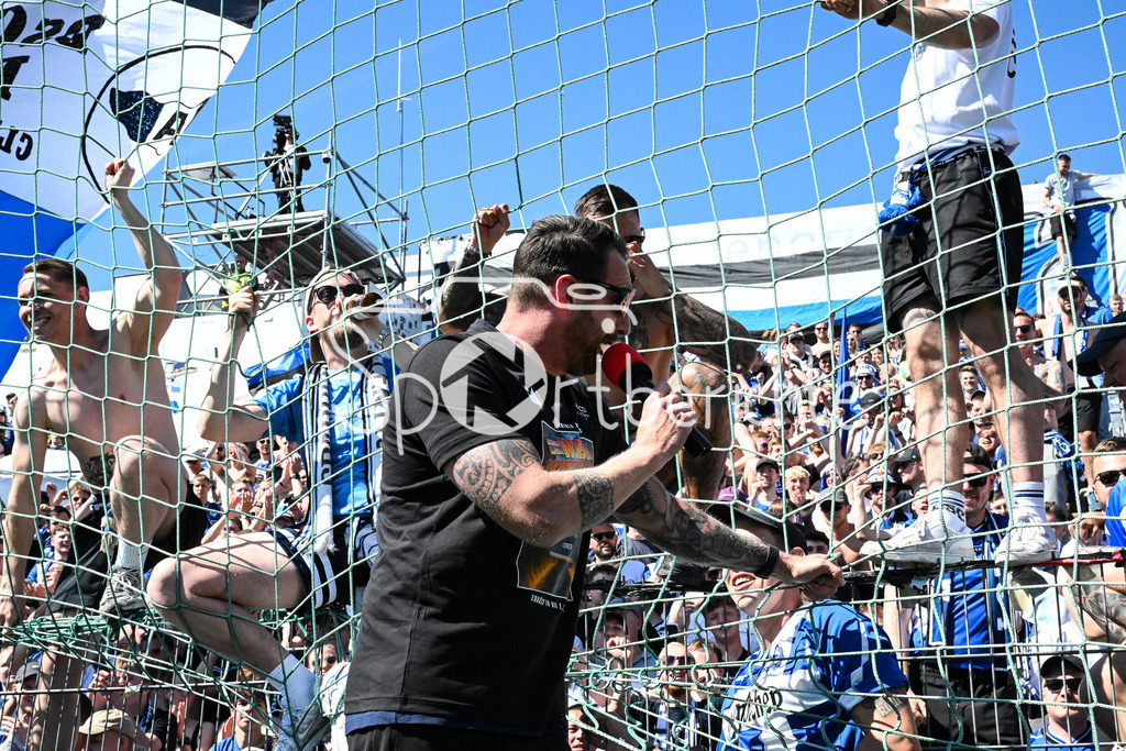 SpVgg Unterhaching - Arminia Bielefeld | Die Mannschaft aus Bielefeld feiert zusammen mit den Fans den Sieg und den Aufstieg in Unterhaching / Bierdursche / Bier / Freude / Happy / Gluecklich / 3. Liga: SpVgg Unterhaching - Arminia Bielefeld, Uhlsport Park am 11.05.2025 / Grenzenloser Jubel / Michel KNIAT Trainer Arminia Bielefeld mit Mikrofon auf dem Zaun