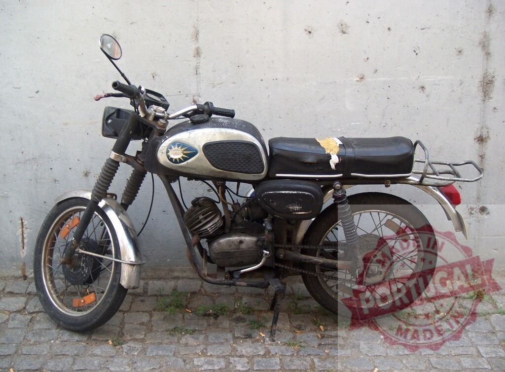 Vintage motorcycle parked against concrete wall showing signs of age and wear | Old motorcycle parked on cobblestone street with torn seat and weathered paint, evoking nostalgia and a sense of history - Realisiert mit Pictrs.com