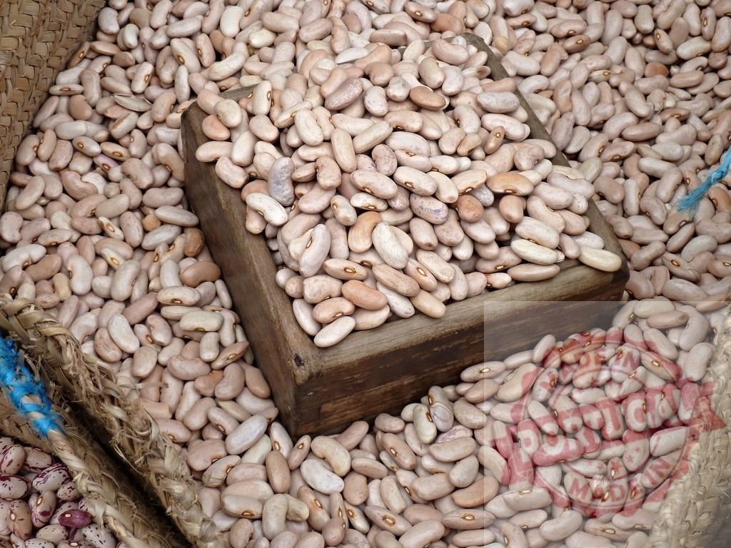 Dry pinto beans with wooden scoop at market | Dry pinto beans filling a woven basket with a wooden scoop, ready for sale - Realized with Pictrs.com