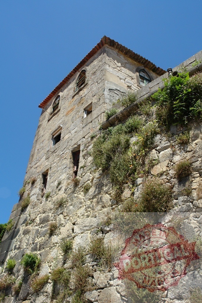 Historic stone building wall with green vegetation under blue sky | Old stone building wall with small attic windows covered in green plants, under clear blue sky - Realisiert mit Pictrs.com