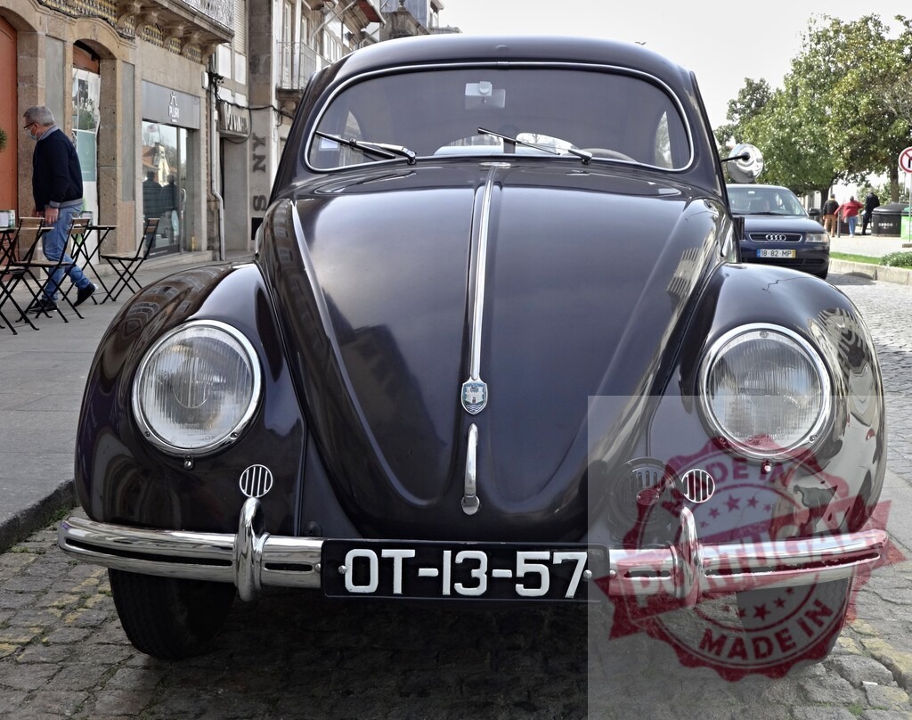 Classic Volkswagen Beetle parked on a cobblestone street | Front view of a shiny, dark-colored classic Volkswagen Beetle parked on a European cobblestone street - Realisiert mit Pictrs.com