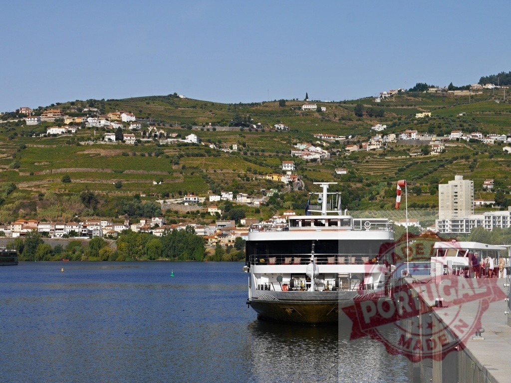 Douro River cruise boat docked by terraced vineyards | Douro River cruise boat docked at Peso da Régua with terraced vineyards and hillside town - Realisiert mit Pictrs.com