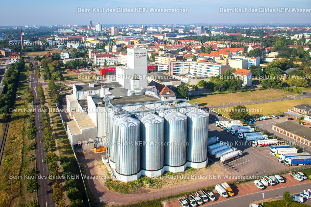 Mühlenwerke Magdeburg Saalestraße-0486 | Blick aus der Luft auf die Mühlenwerke Magdeburg. Im Vordergrund stehen acht markante Stahlsilos, die mit ihrer gleichmäßigen Anordnung und den technischen Konstruktionen ein prägnantes industrielles Motiv bilden.Die großen Silos prägen das Erscheinungsbild des Mühlenstandortes und zeigen eindrucksvoll die Dimension industrieller Anlagen. Aus der Luft werden die Anordnung der einzelnen Behälter, die technischen Verbindungen und die Einbindung in das gesamte Betriebsgelände besonders deutlich.Das Motiv steht beispielhaft für die industrielle Seite Magdeburgs und zeigt, wie sich auch funktionale Produktions- und Lageranlagen fotografisch interessant darstellen lassen. Die klare Geometrie der Stahlsilos verleiht dem Luftbild dabei eine besonders markante Bildwirkung. - Realisiert mit Pictrs.com