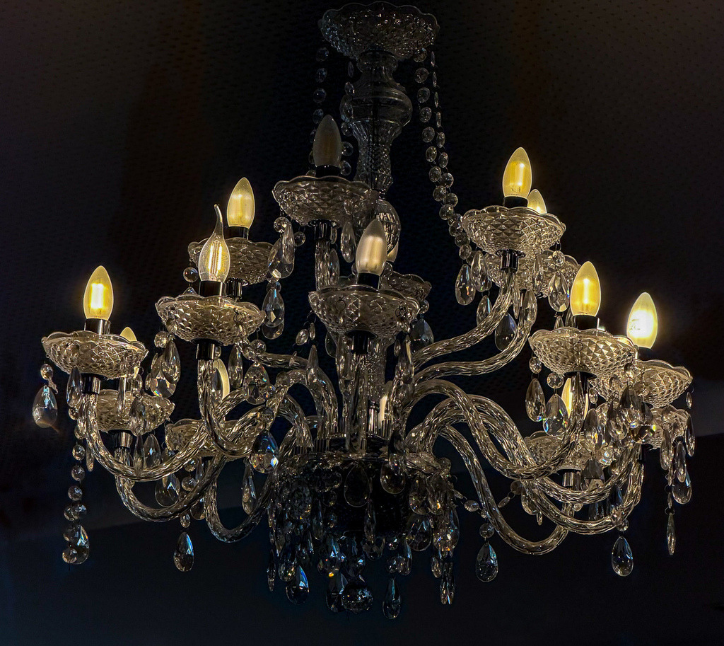 Crystal Chandelier Elegance | A luxurious crystal chandelier glowing softly against a dark background, combining symmetry, glass reflections and warm light into an elegant interior composition. - Realisiert mit Pictrs.com