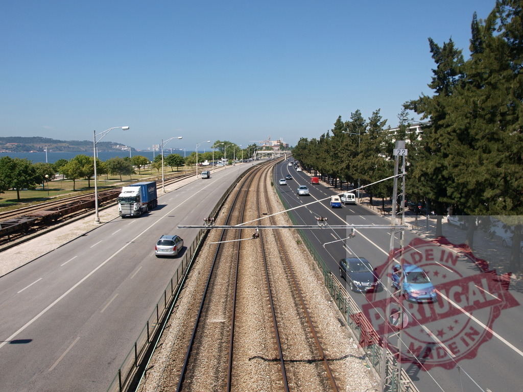 Lisbon city combining road and rail transportation. Lisbon - Portugal | Busy multi-modal transportation corridor with road and railway tracks in Lisbon - Realized with Pictrs.com
