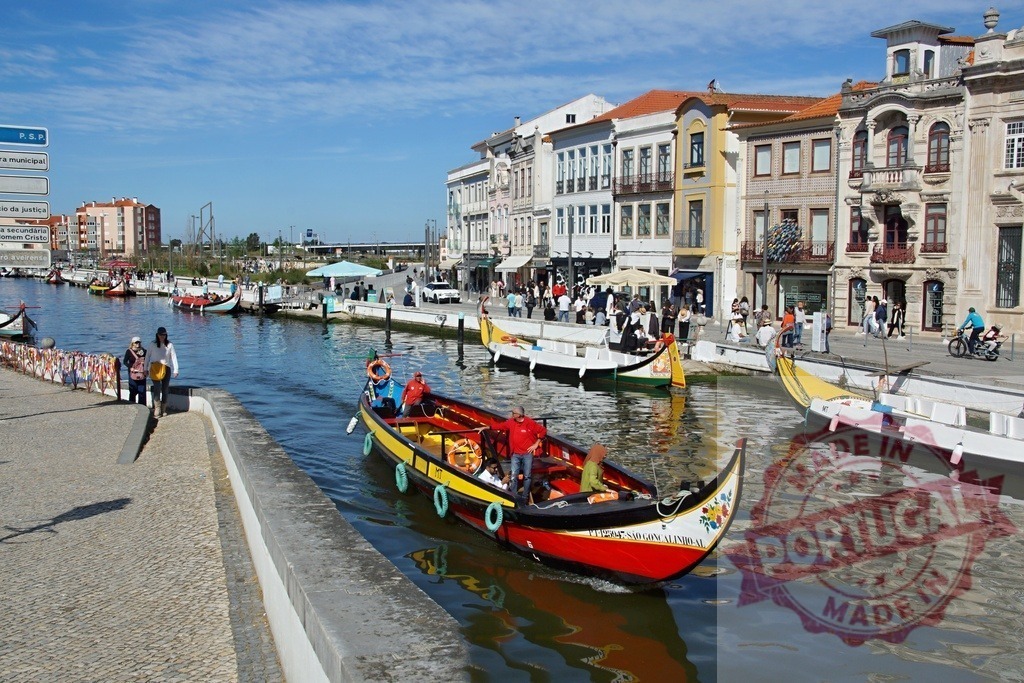 Aveiro moliceiro boat navigating a canal in Portugal. Aveiro - Portugal | Colorful moliceiro boat carrying tourists along an urban canal in Aveiro, Portugal - Realisiert mit Pictrs.com