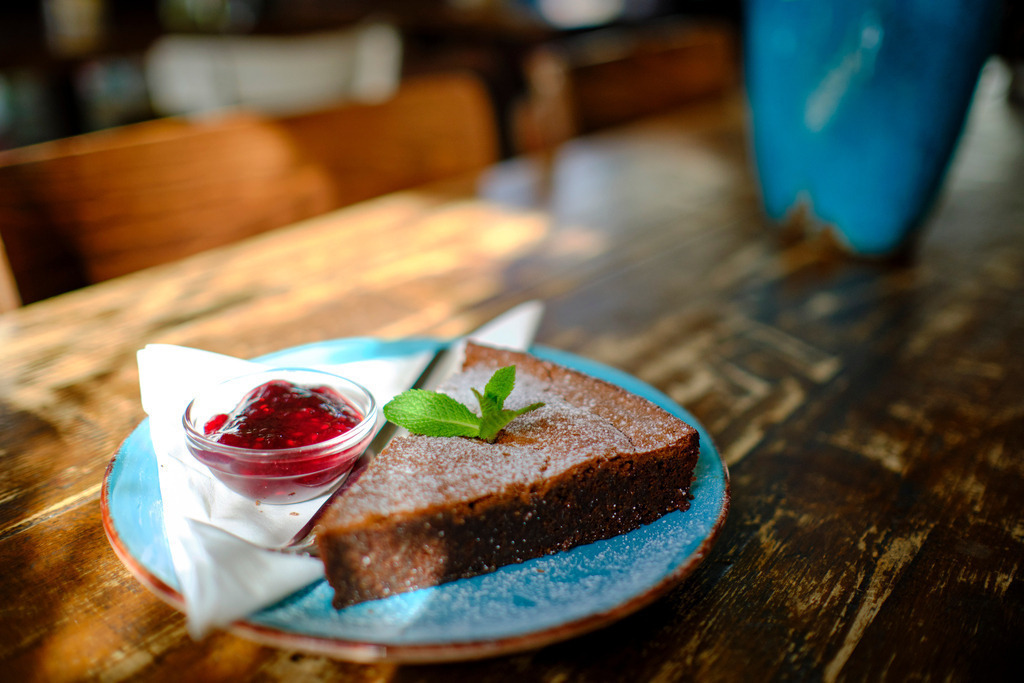 Cafe Mima | Wien, Austria - March 21, 2019: Cafe Mima; eine Blumenvase und ein Schokoladenbrownie ohne Mehl steht auf dem Tisch. - Realisiert mit Pictrs.com