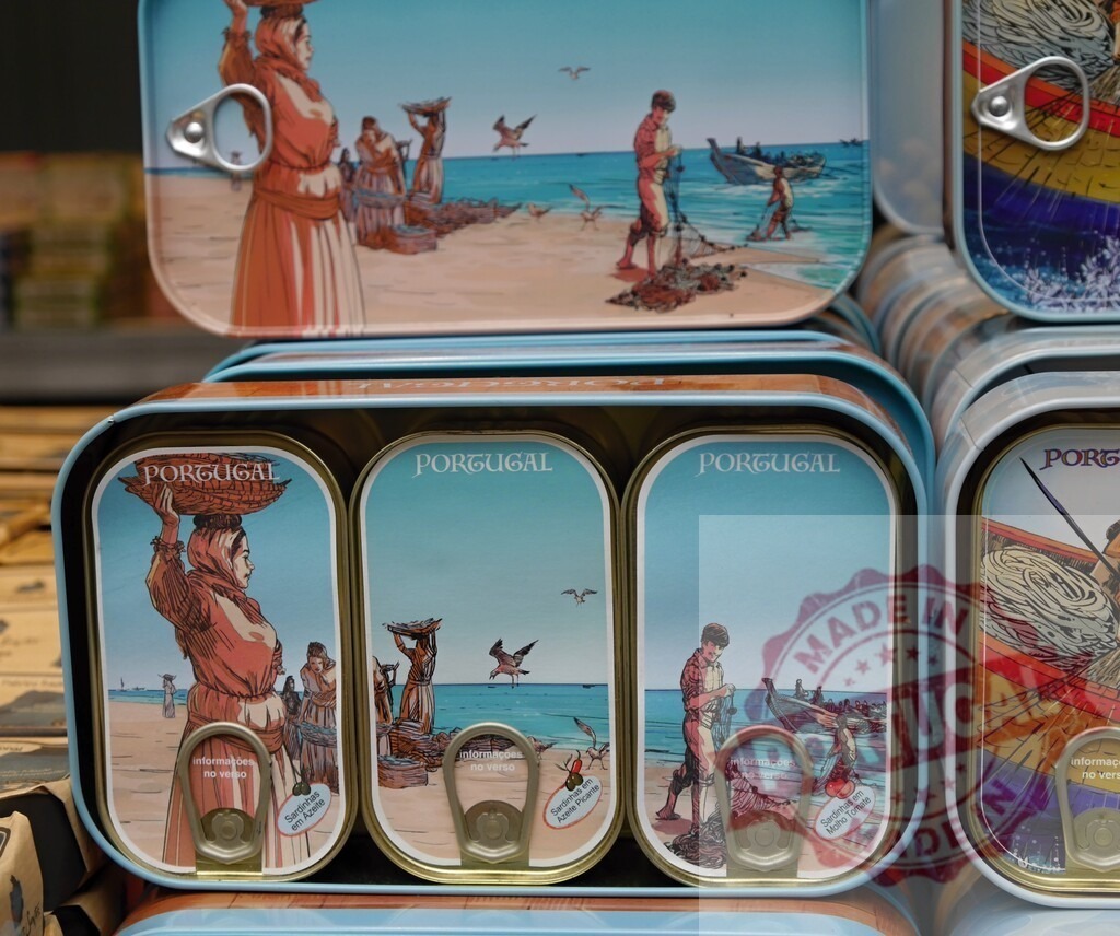 Portugal canned sardines illustrating traditional fishing culture | Stacked souvenir sardine tins featuring vintage illustrations of Portuguese fishing scenes - Realisiert mit Pictrs.com