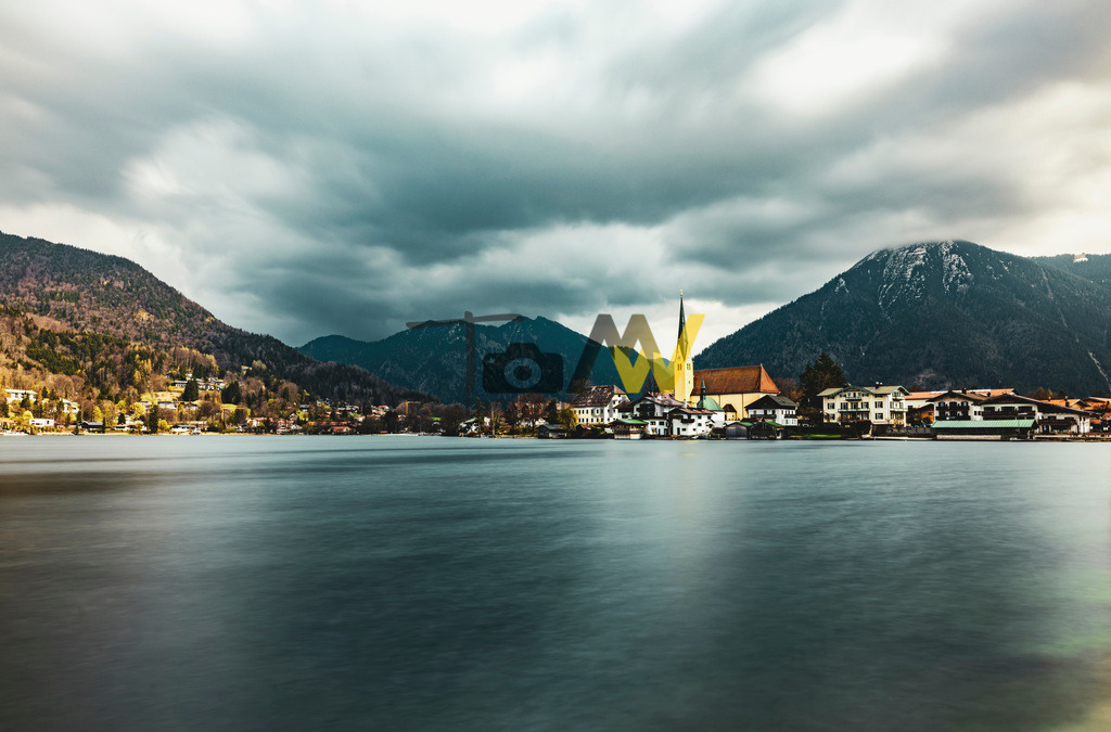 Rottach-Egern am Tegernsee----------Kirche und Wallberg II | Blick über den Tegernsee auf die Ortschaft Rottach-Egern mit der schönen Kirche St. Laurentius. Im Hintergrund thront der Wallberg.Die Abbildung zeigt den Tegernsee in Bayern, Deutschland, mit Blick auf die Stadt Tegernsee und Rottach-Egern. Der Tegernsee liegt etwa 50 Kilometer südlich von München in den Bayerischen Voralpen. Er gilt als einer der saubersten Seen Deutschlands und ist ein beliebtes ganzjähriges Ziel für Aktivurlauber und Erholungssuchende. Die Stadt Tegernsee liegt am Ostufer, während sich Rottach-Egern am Südufer befindet, umgeben von Bergen wie dem Wallberg. Die Region ist bekannt für ihre malerische Landschaft, das anerkannte Heilklima und vielfältige Freizeitangebote.  - Realisiert mit Pictrs.com