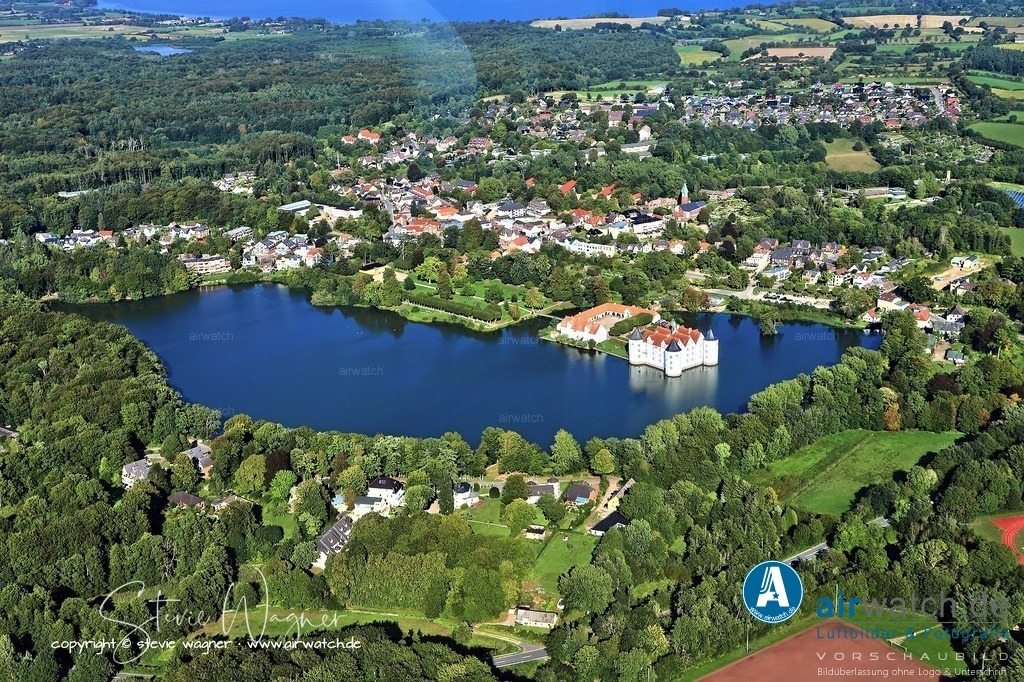 Luftbild Schloss Glücksburg - Die eigentliche Baugeschichte des heutigen Schlosses beginnt 1582 | Die eigentliche Baugeschichte des heutigen Schlosses beginnt 1582, als der dänische König Friedrich II. seinen Bruder Johann, genannt Hans der Jüngere, Herzog von Schleswig-Holstein-Sonderburg, mit dem Kloster und den umliegenden Ländereien belehnte. Johann begann sofort mit dem Abriss der Klosteranlagen und ließ das Schloss Glücksburg nach französischen Vorbildern errichten. Der Baumeister war Nikolaus Karies, der den Bau von 1583 bis 1587 abschloss.