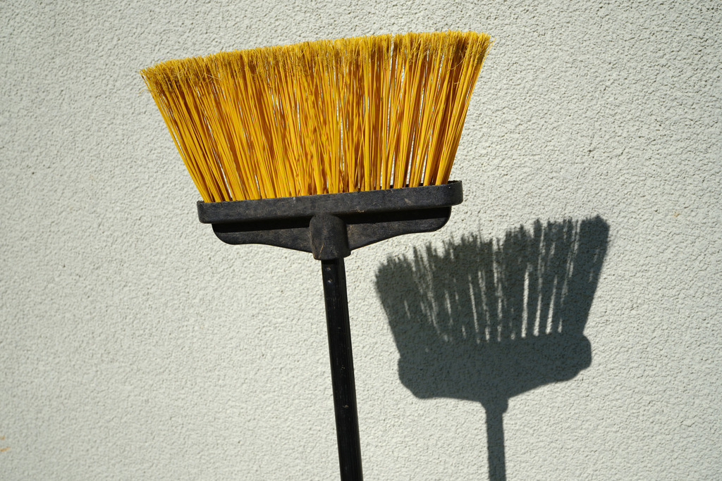 Schatten eines gelben Besens auf der Hauswand | Austria - April 19, 2025: Schatten eines gelben Besens auf der Hauswand. - Realisiert mit Pictrs.com