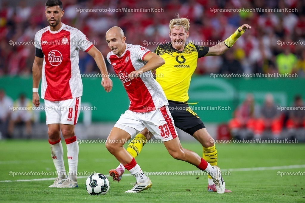 DFB18082501092 | 2025.08.18, Fußball, 1.Runde DFB-Pokal, Rot-Weiss Essen - Borussia Dortmund, Stadion Hafenstraße, Saison 2025 2026: Tobias Kraulich&nbsp;(Rot-Weiss Essen #33) im Zweikampf gegen  Julian Brandt&nbsp;(BVB #10)  DFB regulations prohibit any use of photographs as image sequences and or quasi-video.