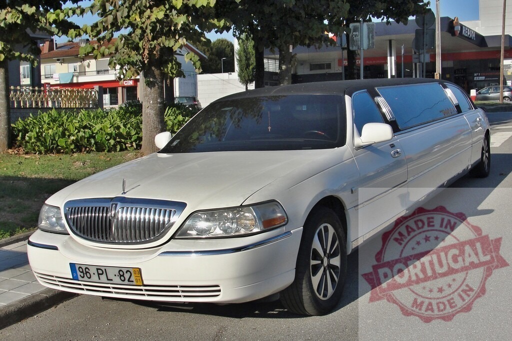 White limousine parked on urban street, offering luxury travel | White Lincoln Town Car limousine parked on a sunny urban street during the day - Realisiert mit Pictrs.com