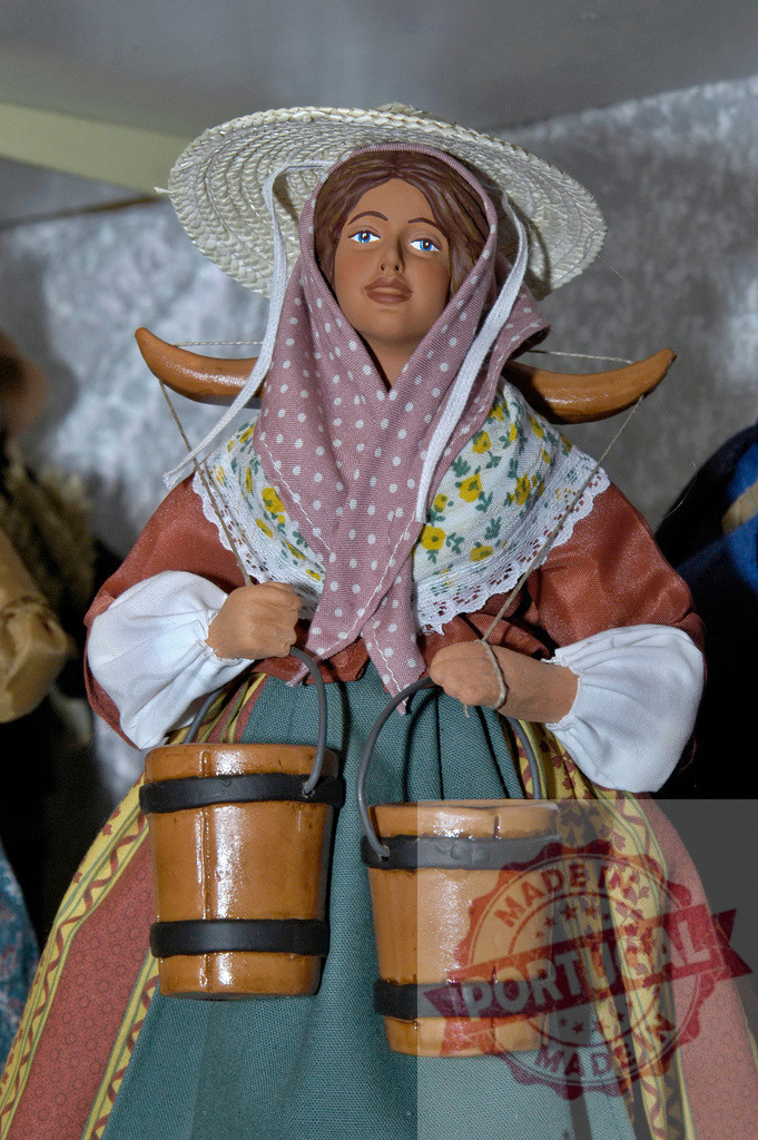 Woman figurine carrying two wooden buckets with yoke on shoulders | Terracotta figurine of a woman wearing traditional clothes and carrying two wooden buckets with yoke on shoulders - Realized with Pictrs.com