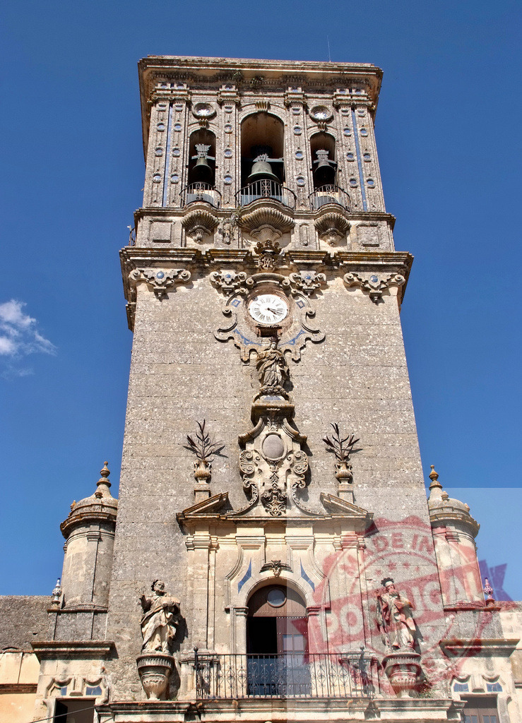 San Pedro Church Tower baroque architecture bell tower. Espana - Cadiz | San Pedro Church Tower displaying baroque details and a clock against a clear blue sky - Realized with Pictrs.com