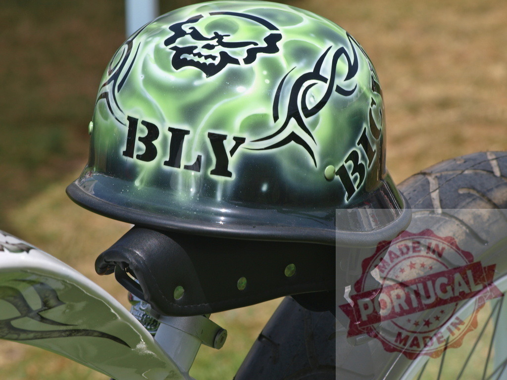 Custom green motorcycle helmet with skull design | Custom green motorcycle half helmet with skull and tribal airbrush design resting on a bike seat - Realisiert mit Pictrs.com