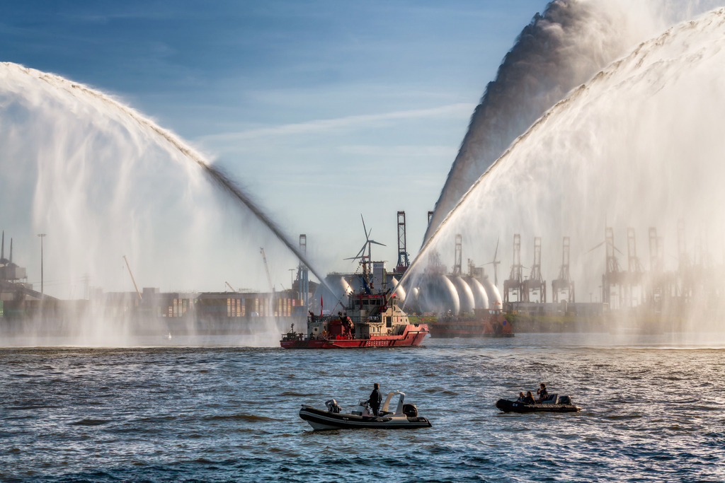 10250502 - Wasserspektakel | Das Feuerlöschboot „Branddirektor Westphal“ inszeniert ein faszinierendes Wasserspektakel vor der Kulisse des Hamburger Hafens.    Bitte wähle „Bestellen“, um dieses Wandbild individuell zu konfigurieren – in Größe, Material und Ausführung.