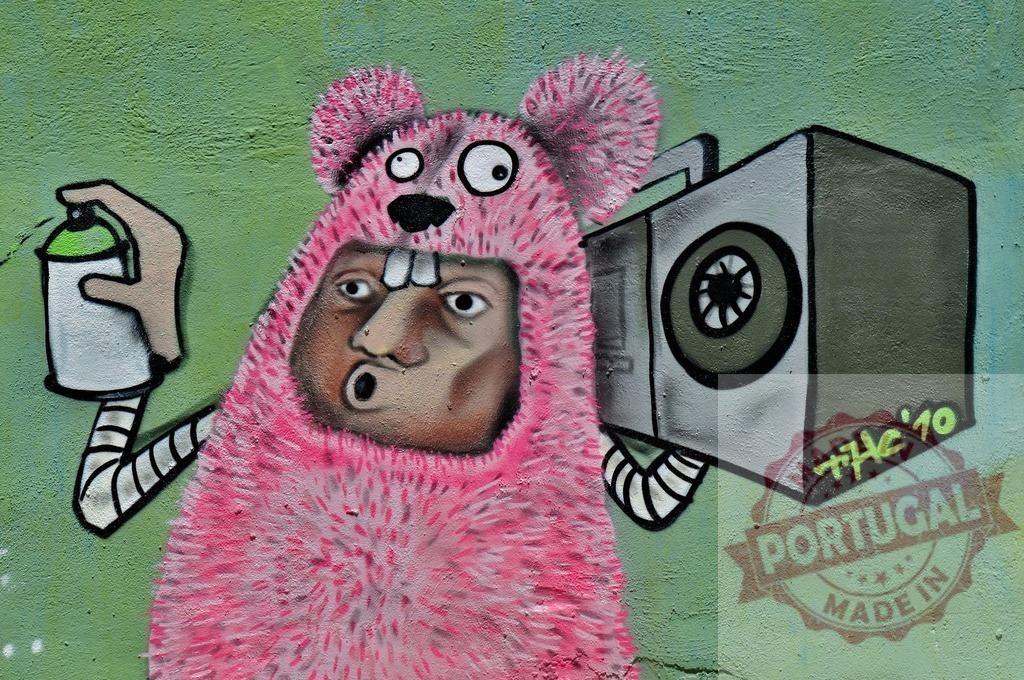 Pink monster with boombox painting graffiti art on a green wall | Street artist painting a pink furry monster with a boombox on a green wall - Realized with Pictrs.com