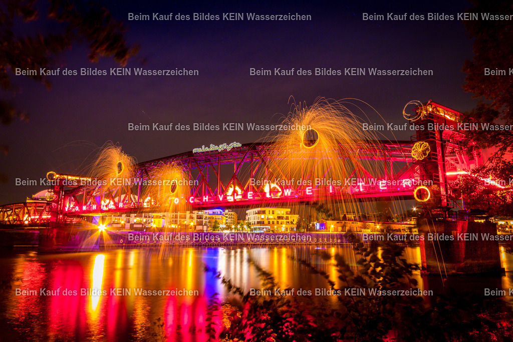 Lichtkunst_Daniel_Hubbrücke_3520-3 | Diese Langzeitbelichtung zeigt die historische Hubbrücke in Magdeburg während einer außergewöhnlichen nächtlichen Inszenierung. Das technische Denkmal präsentiert sich in einem spektakulären Zusammenspiel aus Licht, Feuer und Architektur. Die markante Stahlkonstruktion wird durch kunstvolle Illuminationen eindrucksvoll hervorgehoben und verwandelt sich in ein faszinierendes Gesamtkunstwerk. Insgesamt 18 Lichtkünstler mussten ihre Requisiten zeitgleich entzünden, um die gewünschte Wirkung zu erzielen. Flammen, Lichtspuren und Effekte verschmolzen zu einer beeindruckenden Inszenierung, die die historische Brücke in ein völlig neues Licht rückte.Die Hubbrücke zählt zu den bekanntesten technischen Bauwerken Magdeburgs. Die Kombination aus historischer Ingenieurbaukunst und moderner Lichtkunst verleiht der Aufnahme eine außergewöhnliche Atmosphäre.Dieses Privatfoto des Lichtkünstlers Daniel Lehmann dokumentiert einen seltenen Moment, in dem Technik, Kultur und Kunst auf einzigartige Weise miteinander verschmelzen und die Hubbrücke zu einem der spektakulärsten Fotomotive Magdeburgs machen - Realisiert mit Pictrs.com