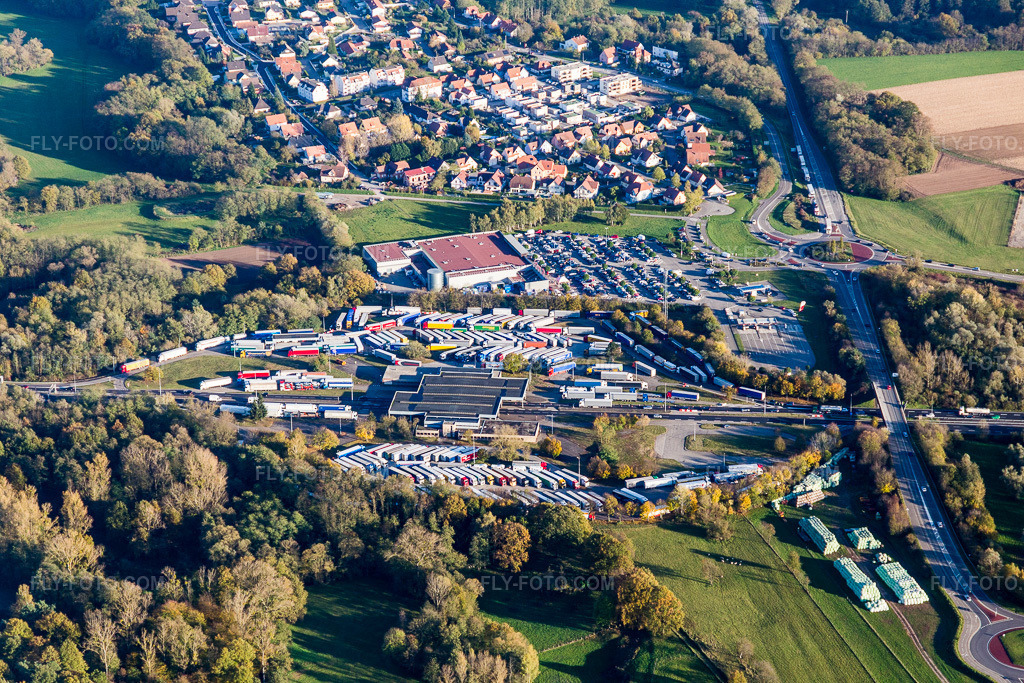 Aerial view: Parked trucks at the A35 motorway toll station with the Bienwald Federal Police station (formerly the German-French border crossing Lauterbourg) in Scheibenhard in the state Bas-Rhin, France. – Photo: IMG_104381.jpg taken on 10/31/2017 by Werner Riehm/FLY-FOTO.com – Resolution of the original: 5472 x 3648 px