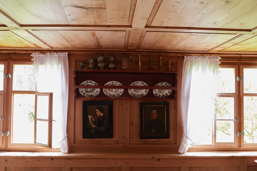 Heimatmuseum Bezau | Bezau, Austria - July 27, 2017: Heimatmuseum Bezau, Blick in das Wohnzimmer auf eine Wand mit Familienbilder, Tellerbord, Zinnkrügen und Kerzenhalter. - Realisiert mit Pictrs.com