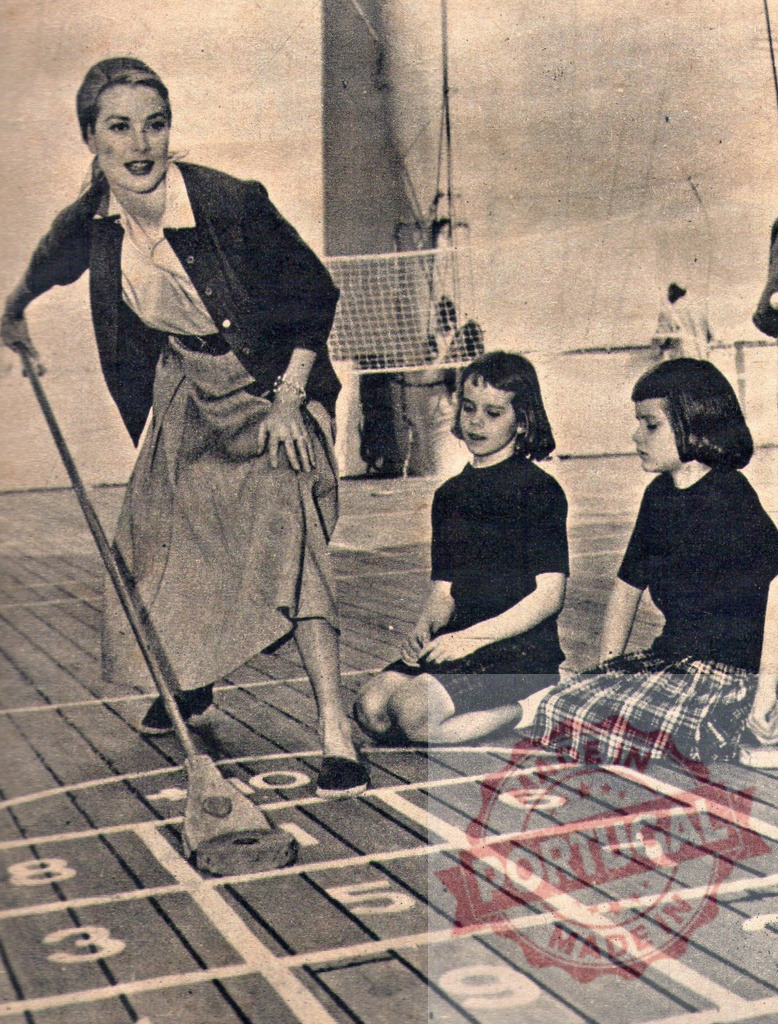 Grace Kelly playing shuffleboard with her daughters on the deck of a ship | Grace Kelly pushes a shuffleboard disc while her daughters watch, during a family vacation on a ship - Realized with Pictrs.com