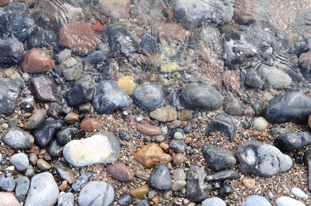 Strandboden mit Steinen im Wasser | Der Übergang zwischen Strand und Wasser wird als Küste beschrieben - Realisiert mit Pictrs.com
