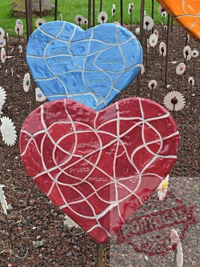 Ceramic mosaic hearts representing memorial and remembrance | Two ceramic mosaic hearts with names inscribed, honoring love and remembrance in a garden - Realized with Pictrs.com