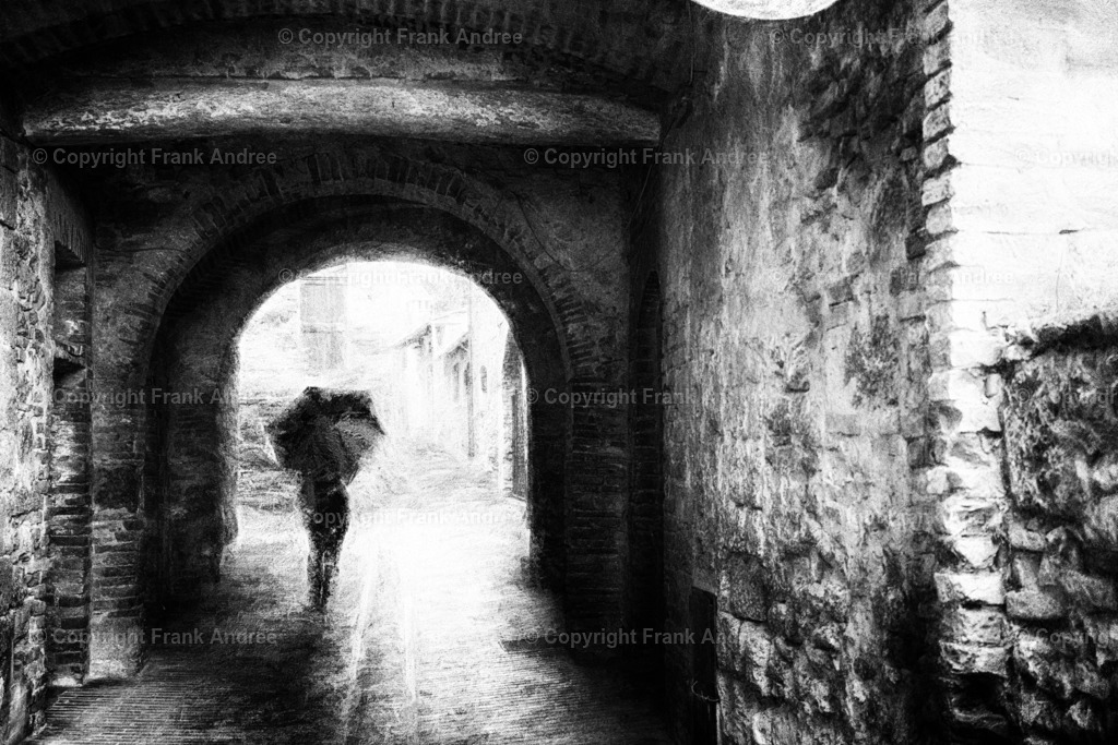 Regen in San Gimignano | Eine Frau mit Regenschirm geht durch einen Hausdurchgang in der Altstadt von San Gimignano Toskana. Impressionistische Straßenfotografie aus Italien in schwarz weiß - Realisiert mit Pictrs.com