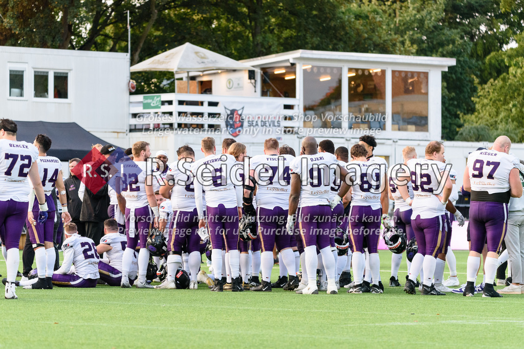 RS-1-004308 | Frankfurter Spieler in weiß-lilanen Jerseys stehen nach dem Spiel im Huddle auf dem Platz vor dem Sea Devils Banner und der VIP-Loge.