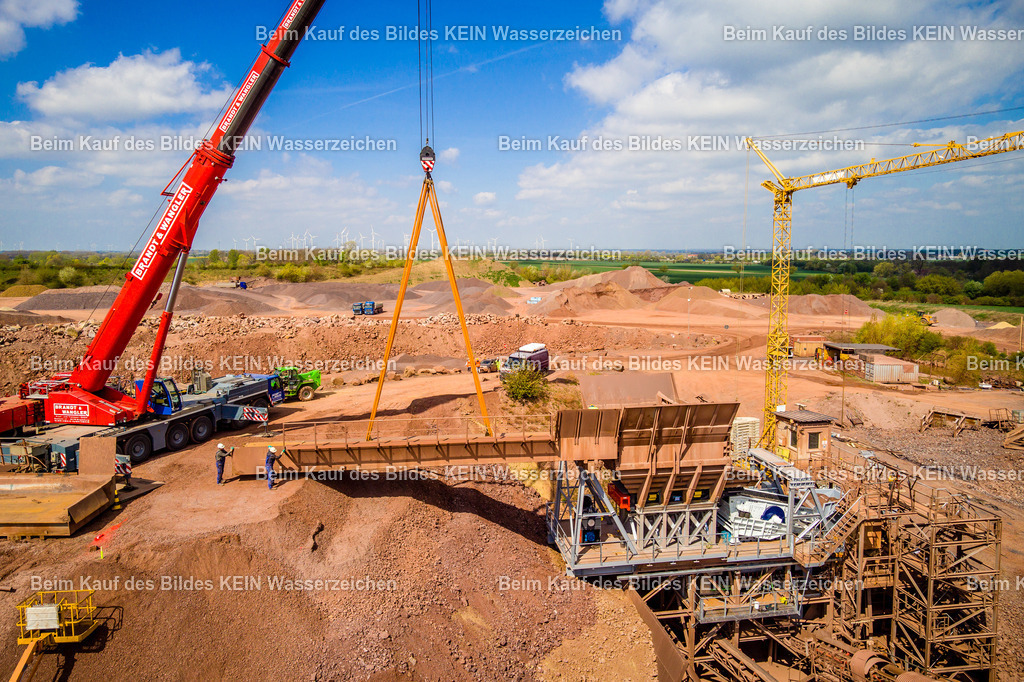 Mammendorf Brecher 2 Drohne-0057 | Die Drohnenaufnahme zeigt den Einbau der großen Brücke für die neue Brecheranlage im Steinbruch Mammendorf aus näherer Perspektive. Das Brückenbauteil schwebt am Kran unmittelbar über dem vorgesehenen Einbauort, während die Mitarbeiter den Montagevorgang begleiten und das Bauteil exakt positionieren. Der rote Kran der Firma Brandt &amp; Wangler und der große Turmdrehkran verdeutlichen den erheblichen technischen Aufwand dieses Bauabschnitts.Die Aufnahme zeigt eindrucksvoll das Zusammenspiel von Kran, Monteuren und bestehender Aufbereitungsanlage und dokumentiert einen wichtigen Moment beim Aufbau der neuen Brecheranlage für das im Steinbruch gewonnene Andesitgestein.Die Aufnahme ist Teil des Mitteldeutschen Bildarchivs von Luftbildfotograf Steffen Lehmann. - Realisiert mit Pictrs.com