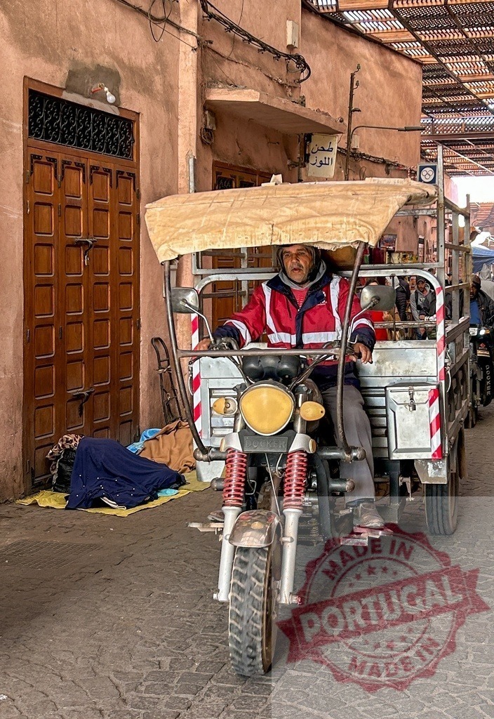 Delivery driver riding a tricycle in Marrakech with a homeless person sleeping on the street | Moroccan delivery driver riding his tricycle in a narrow street of Marrakech with a homeless person sleeping on the ground - Realized with Pictrs.com