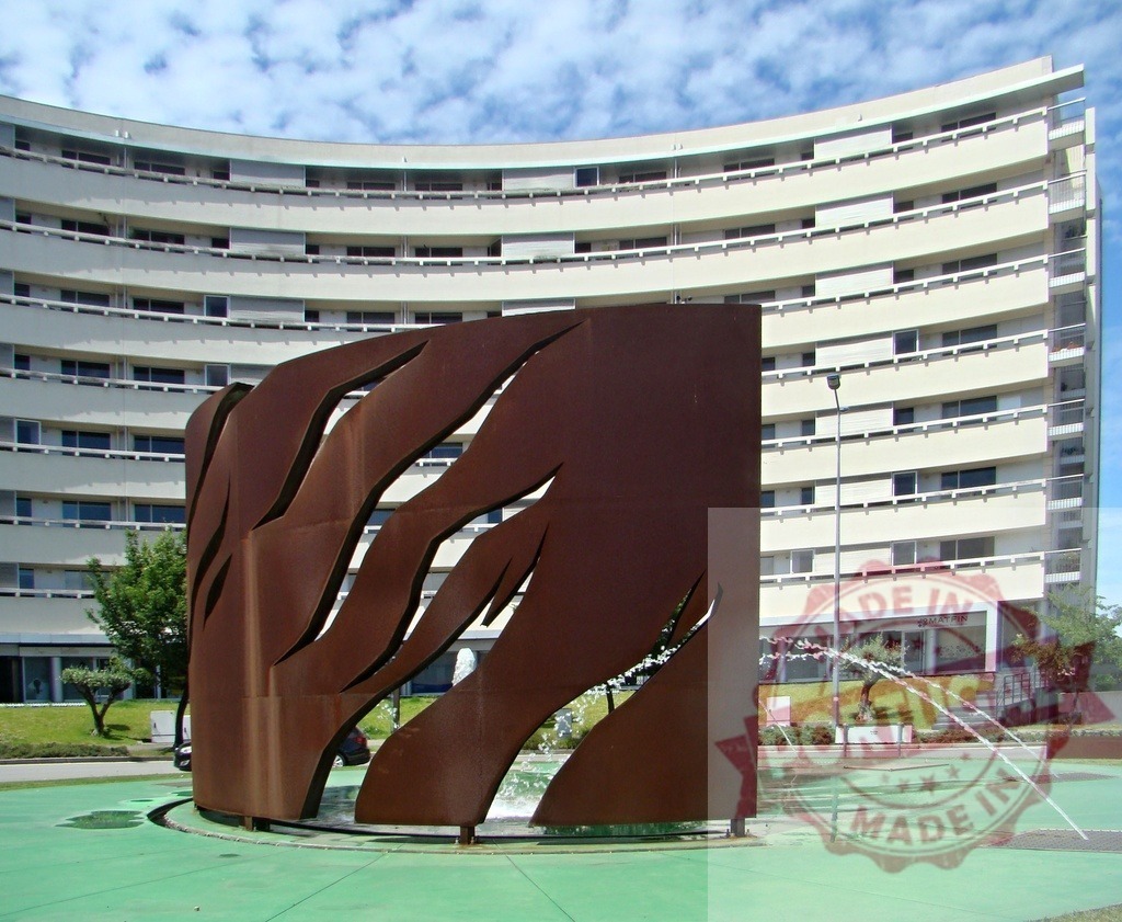 Modern metal sculpture fountain with residential building architecture. Portugal - Norte | Contemporary public art fountain standing in front of modern curved residential buildings - Realized with Pictrs.com