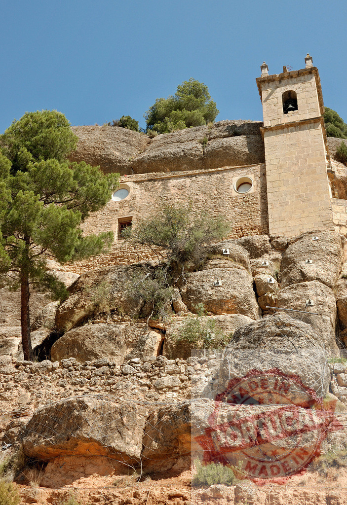 Church built into cliff rock face with bell tower | Ancient stone church carved into rugged cliffside, featuring a bell tower against a clear blue sky - Realisiert mit Pictrs.com