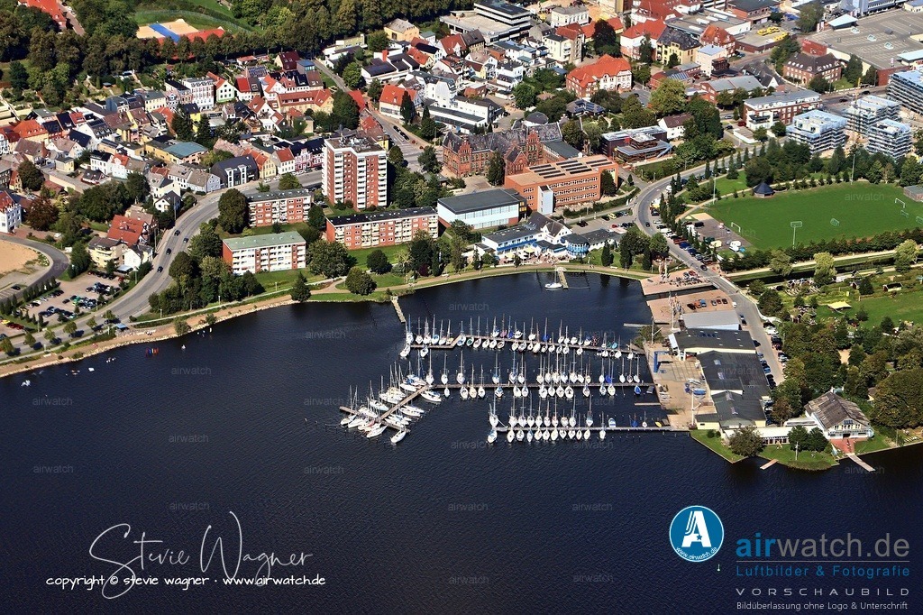 Luftbild Schleswig, Luisenbad, Schleistrasse, Schleswiger Kanu-Club, Segel-Club | Der Schleswiger Kanu-Club „Haithabu“ e.V. ist mit rund 300 Mitgliedern eine lebendige Gemeinschaft für Jung und Alt, die Kanusport in verschiedenen Formen anbietet. Angeboten werden Freizeitpaddeln, Kanu-Polo, Küstenpaddeln sowie Stand-up-Paddling (SUP). Der Club bietet ein gemeinschaftliches Umfeld mit regelmäßigem Austausch und gemeinsamen Touren, direkt an der Schlei gelegen. Mitglieder schätzen das vielfältige Angebot und die familiäre Atmosphäre, die sowohl Einsteigern als auch erfahrenen Paddlern einen guten Raum bietet. Positiv hervorgehoben wird das engagierte Team und die Möglichkeit, den Club persönlich kennenzulernen.