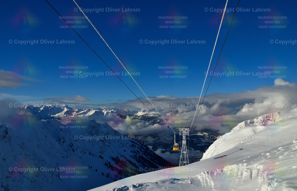 Seilbahnfahrt ins Winterglück | Eine Gondel kommt vom Tal in eine weiße Gebirgslandschaft mit blauem Himmel.