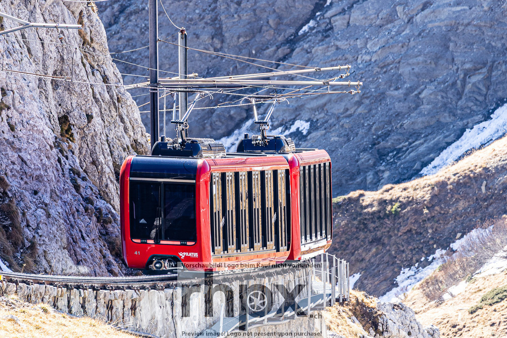 Pilatusbahn am Fels | Technik. Fels. Innovation.Die steilste Zahnradbahn der Welt schraubt sich unaufhaltsam durch die massive Felslandschaft am Pilatus. Das leuchtende Rot der modernen Kabine bildet einen faszinierenden Kontrast zum rauen, grauen Stein des Bergmassivs.Wähle unter "Produktauswahl" dein Wunschformat: Vom klassischen Wandbild über Puzzle &amp; Tassen bis zum digitalen Download (z.B. als Handy-Hintergrund). - Realisiert mit Pictrs.com
