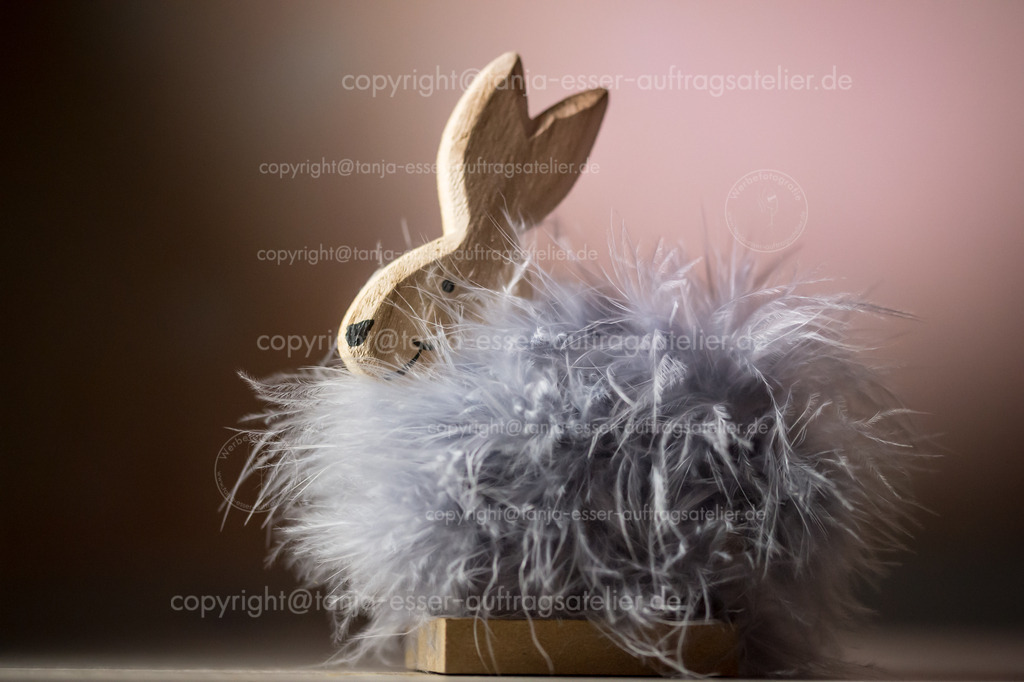 Diva | Osterhase aus Holz mit grauen Federn. Im Studio beleuchtete Hasenfigur vor pinkem Farbverlauf. Textfreiraum und deutliche Struktur.