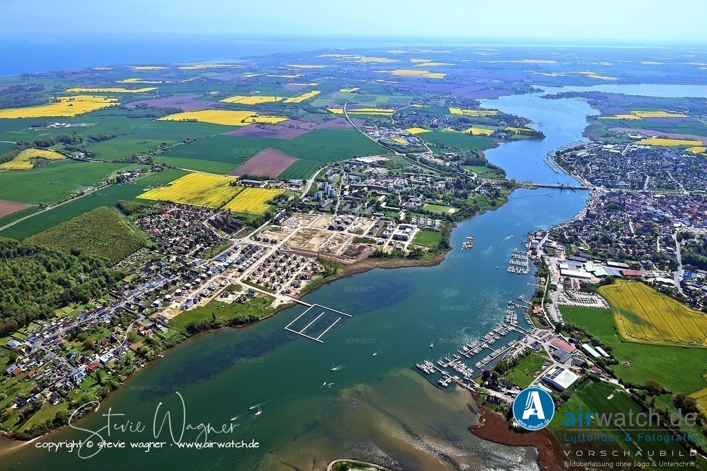 Luftbild Kappeln an der Schlei & Ellenberg | Immobilien in Kappeln-Ellenberg: Schleiterrassen an der Schlei. Das Quartier Schleiterrassen in Kappeln-Ellenberg entsteht auf dem Gelände der ehemaligen Marine-Waffenschule und erstreckt sich entlang der Schlei. Mit einer terrassierten Bebauung und idealer Westlage bietet es exklusive Wohnmöglichkeiten mit Blick auf die Schlei und die gegenüberliegende Marina. Das Areal umfasst etwa 26 Hektar und ist in acht Baugebiete unterteilt, die eine Mischung aus Einfamilienhäusern, Doppelhäusern, Reihenhäusern und Geschosswohnungsbau bieten. Grundstücke reichen von 200 bis 2.000 m²