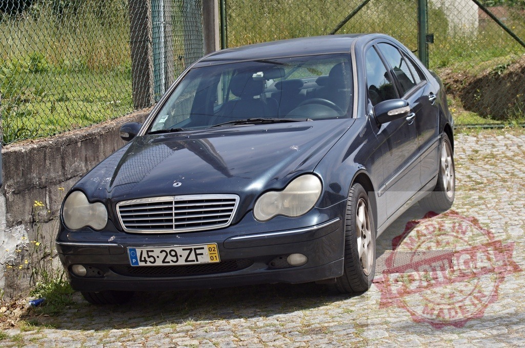 Mercedes-Benz C-Class sedan parked on cobblestone street | Dark blue Mercedes-Benz C-Class W203 sedan parked outdoors on a cobblestone surface - Realized with Pictrs.com