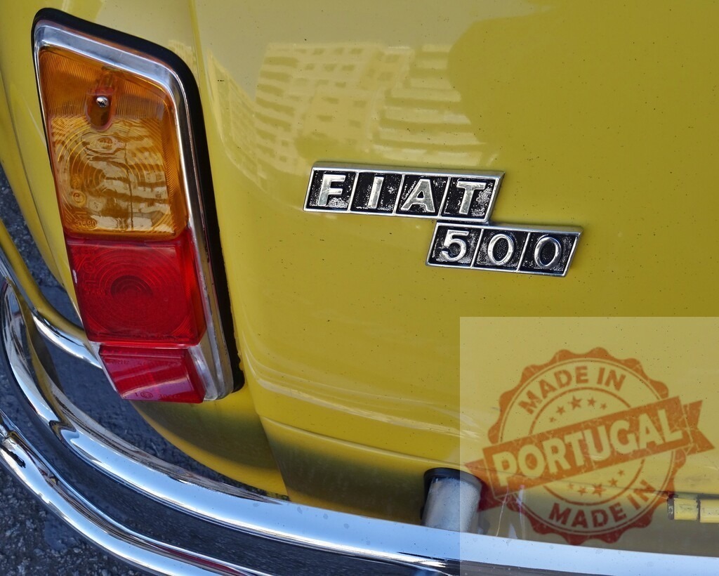 Close-up of Fiat 500 logo and taillight on yellow vintage car | Detail of a yellow Fiat 500 with visible logo and taillight, parked on a street - Realisiert mit Pictrs.com