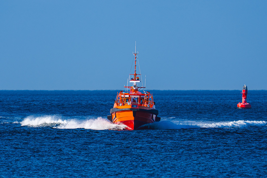 Volle Kraft Voraus: Lotse Warnemünde | Das orangefarbene Versetzboot der Lotsenbrüderschaft Wismar-Rostock-Stralsund bei hoher Fahrt auf der Ostsee. Die Aufnahme zeigt das Boot mit ausgeprägter Bugwelle auf dem Weg zu einem Einsatz im Revier vor Warnemünde. Ein Motiv, das die Dynamik und die tägliche Arbeit des Lotsenwesens bei der Sicherung des Schiffsverkehrs dokumentiert. - Realisiert mit Pictrs.com